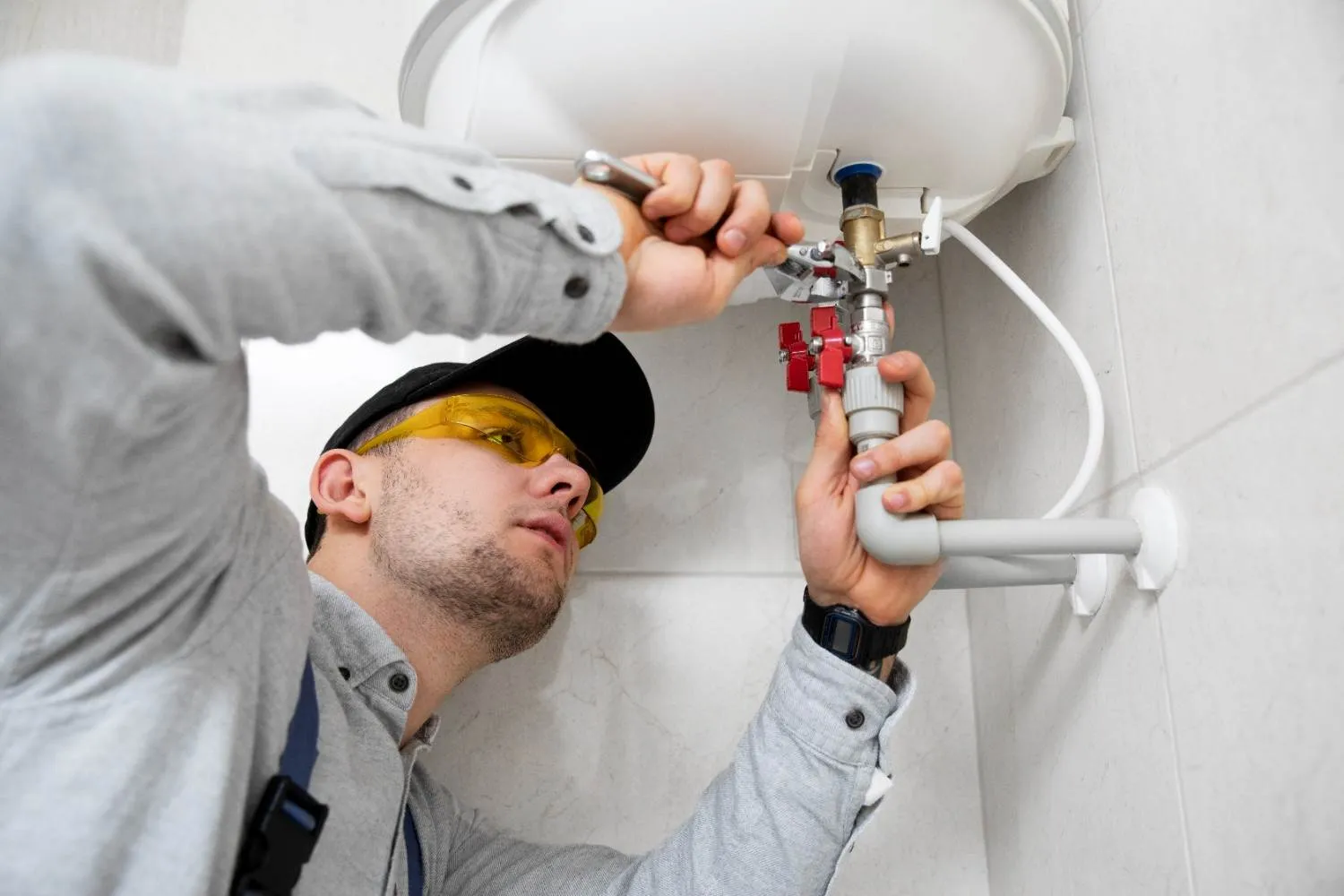 Technician fixing the valves under a wall water heater
